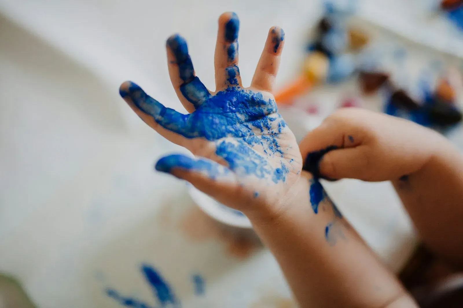 La mano di un bambino dipinta di blu durante un gioco con i colori